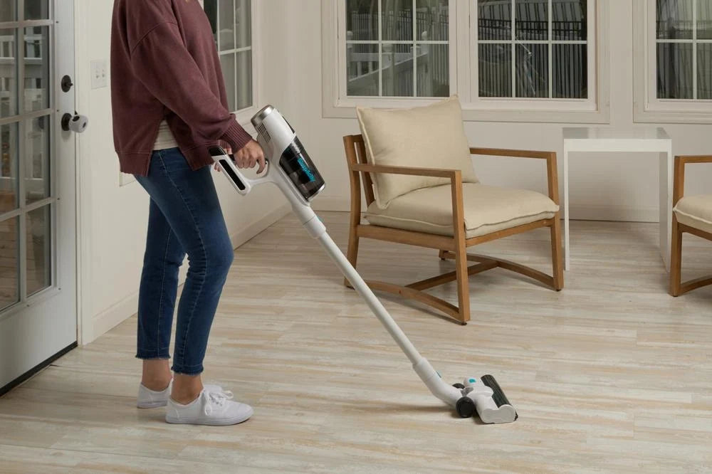 Person vacuuming a light wood floor with a Simplicity S67 cordless bagless stick vacuum