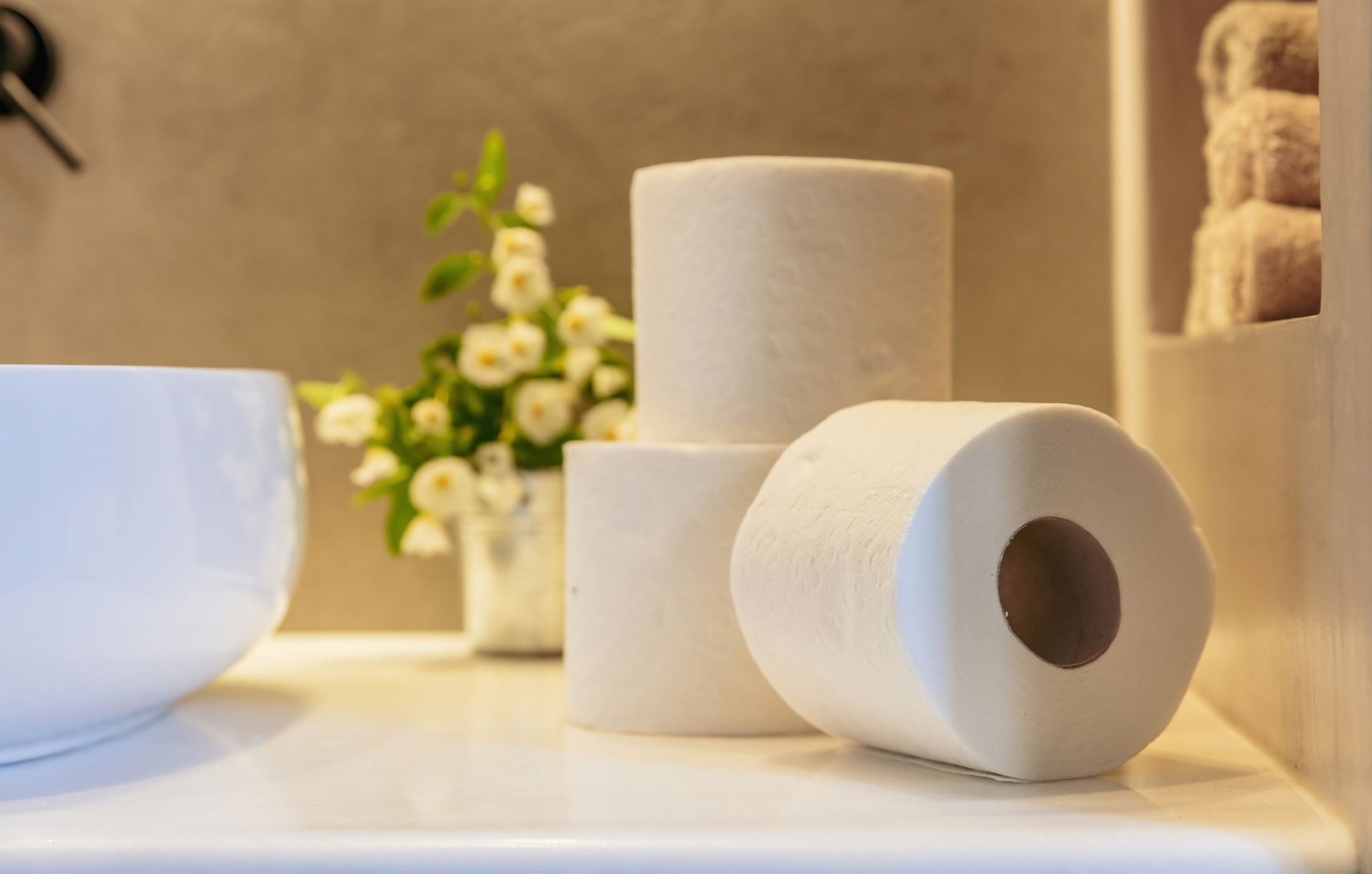 Three rolls of toilet paper on a surface with a blurred background