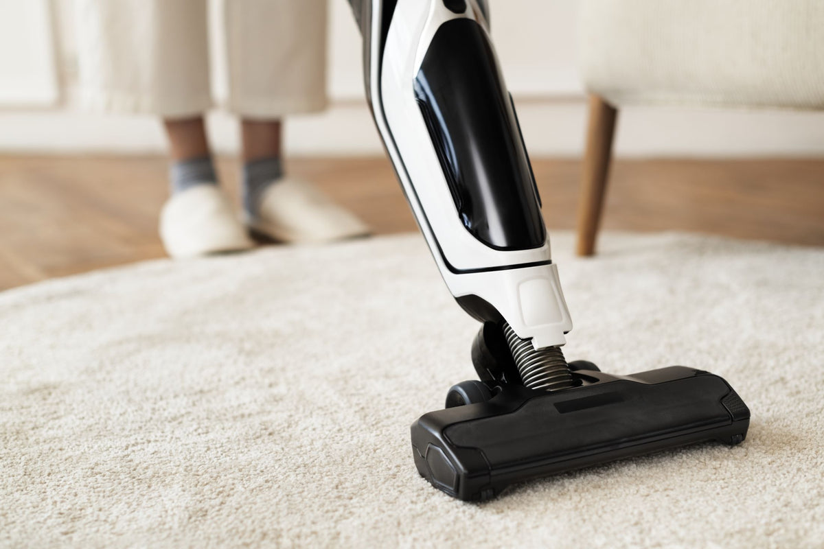Handheld vacuum cleaner being used on a carpeted floor.