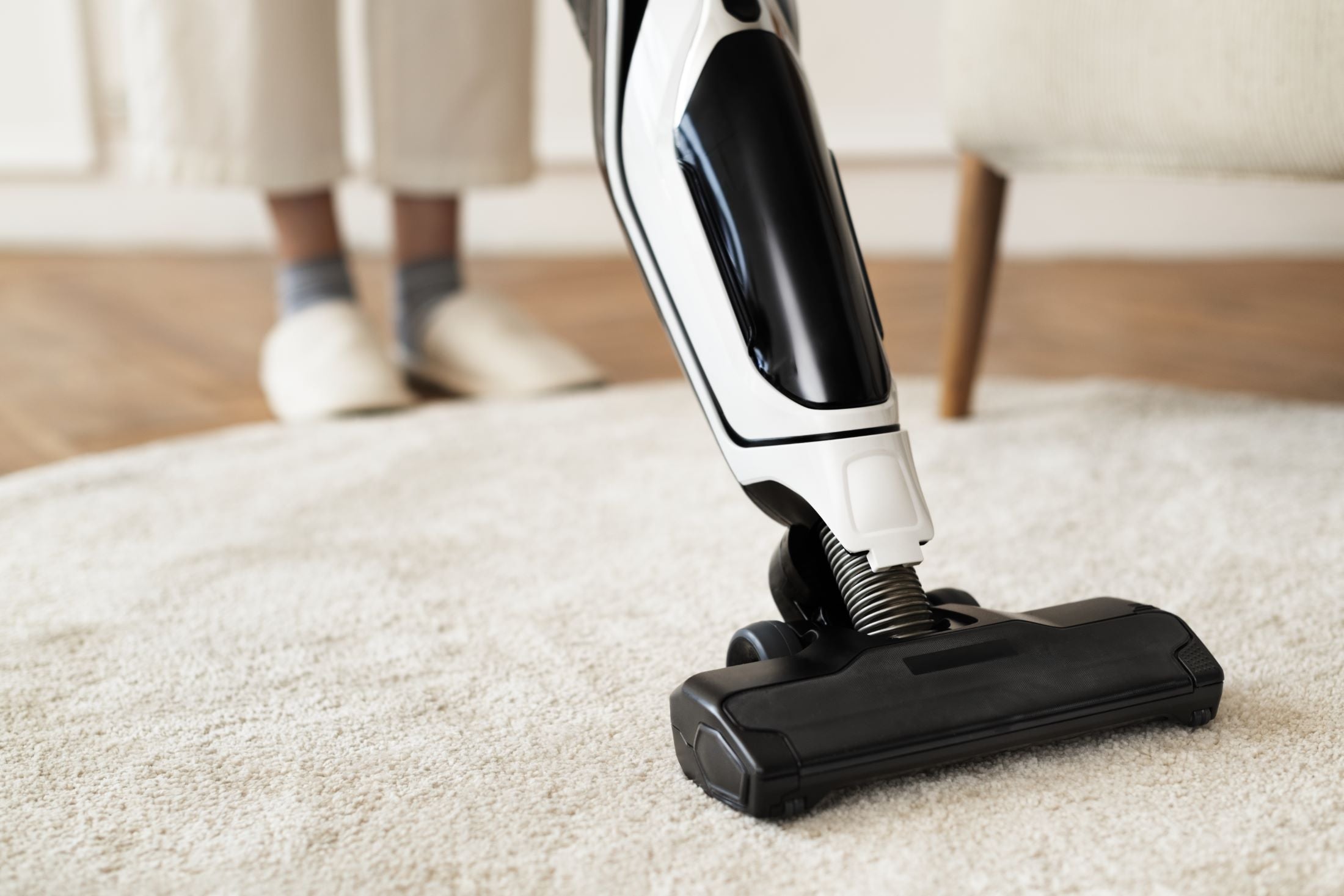 Handheld vacuum cleaner being used on a carpeted floor.